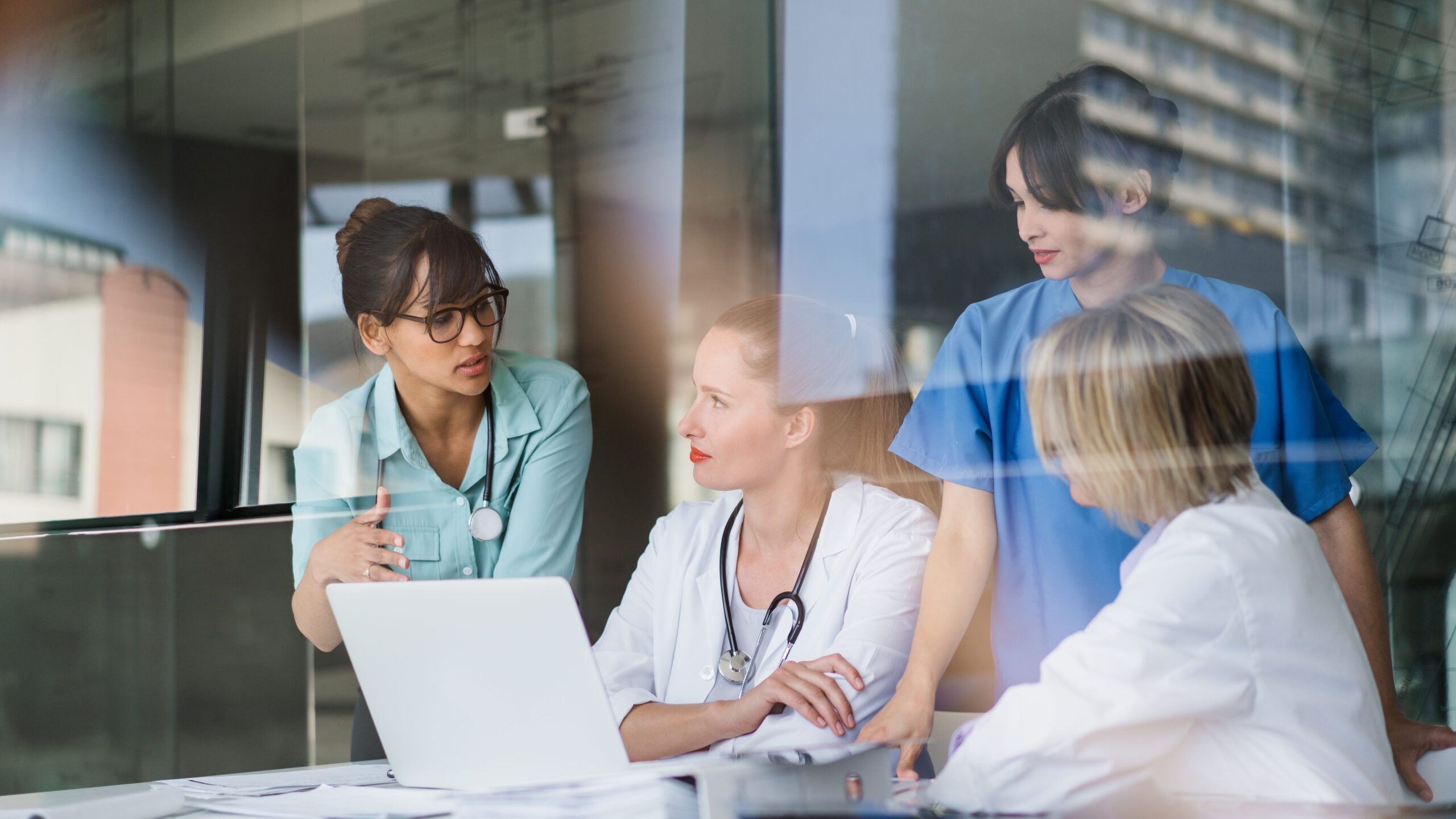 Female Doctors Discussing At Laptop Desk